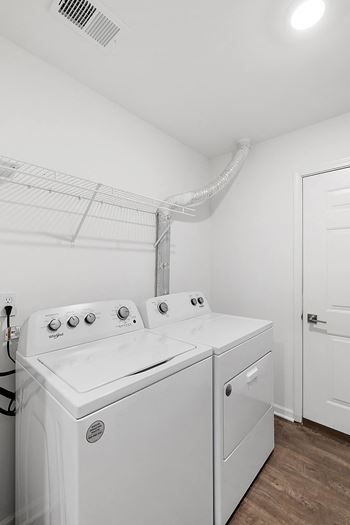 a white laundry room with two washes and a dryer at Cidermill Village Apartments in Rochester Hills, MI 